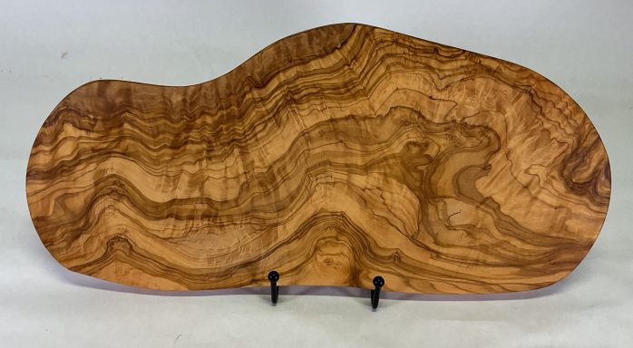 Natural shape olive wood cutting or serving board with beautiful grain pattern.
