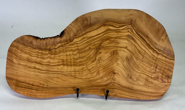 Natural shape olive wood cutting or serving board with beautiful grain pattern.