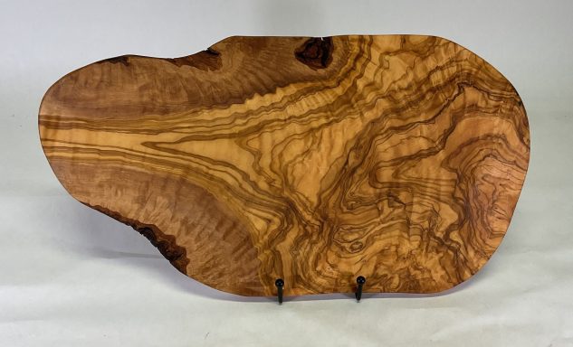 Natural shape olive wood cutting or serving board with beautiful grain pattern.